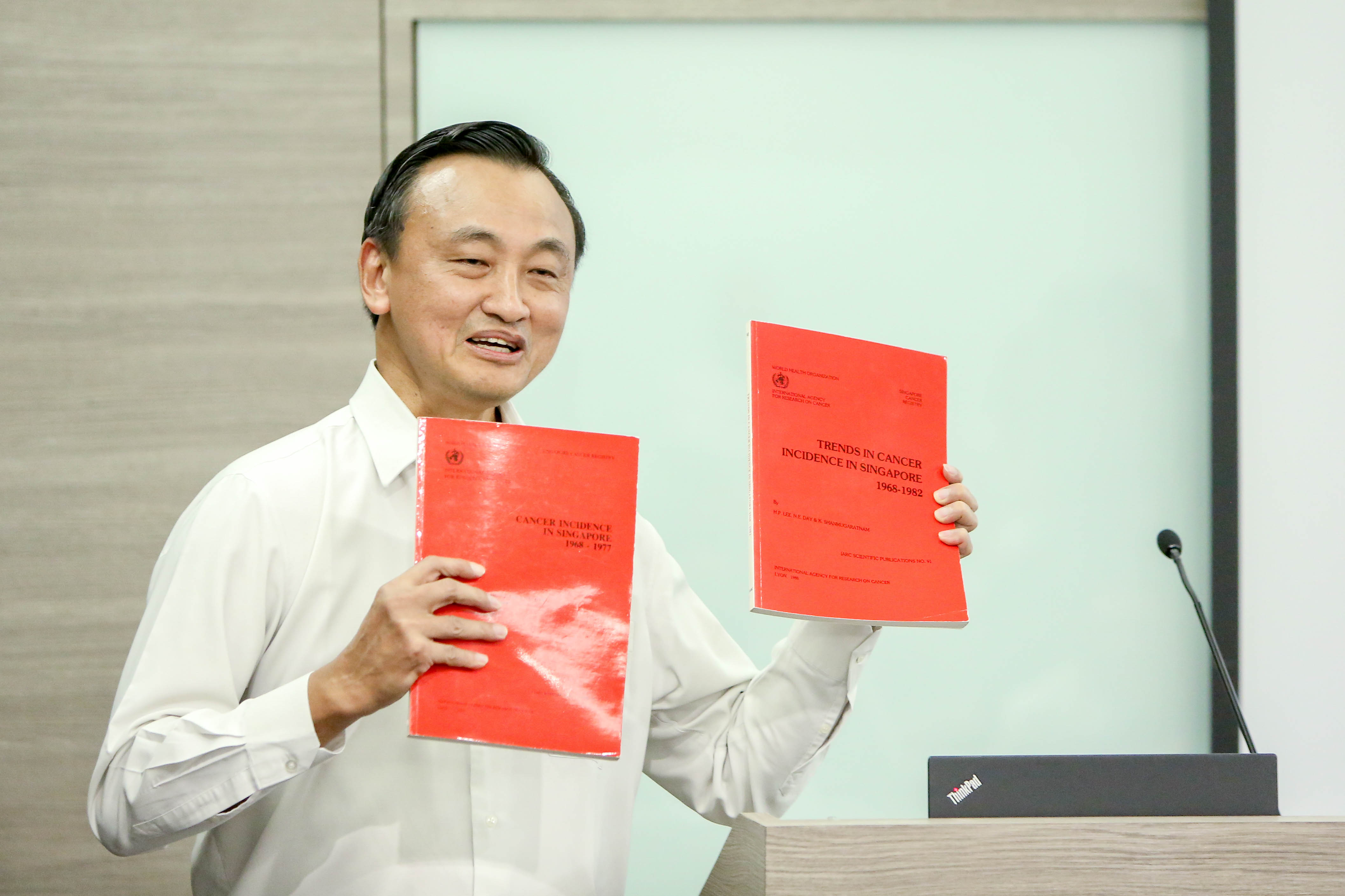 Prof Chia holding the first two monographs by the Singapore Cancer Registry.