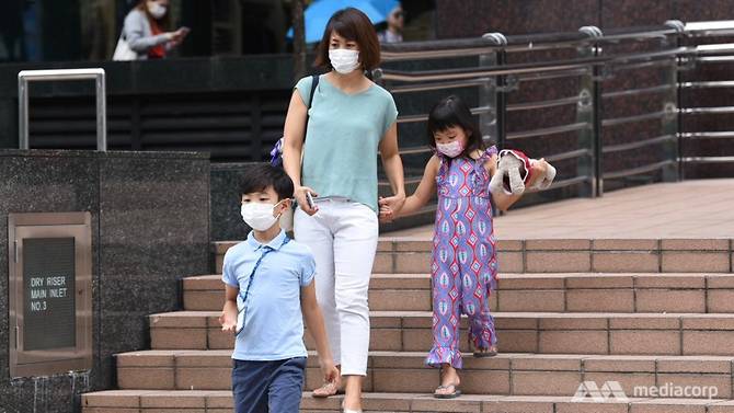 A woman and two children wearing masks and walking down stairs (Photo by Mediacorp)