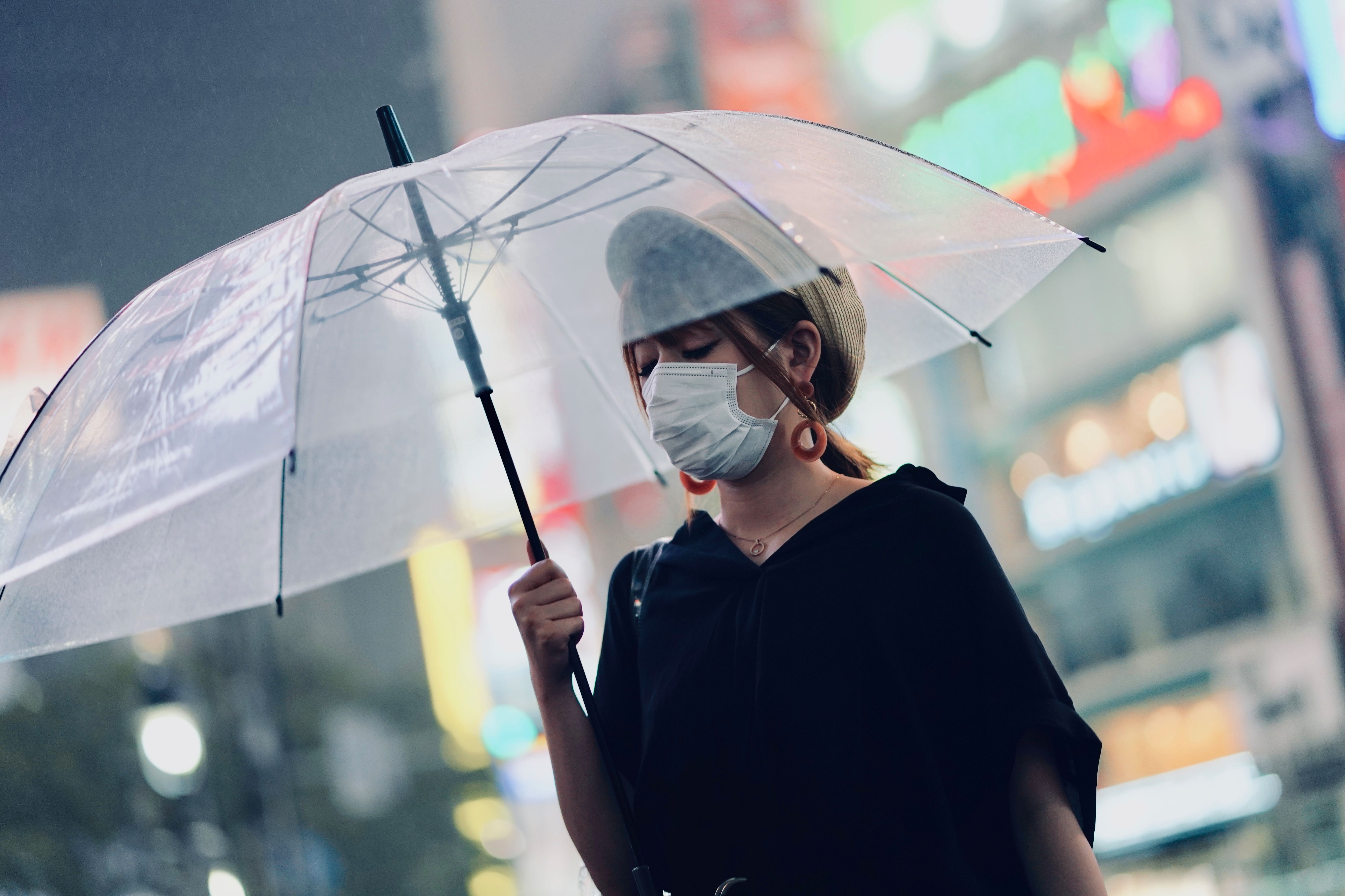 A woman wearing a mask and carrying an umbrella