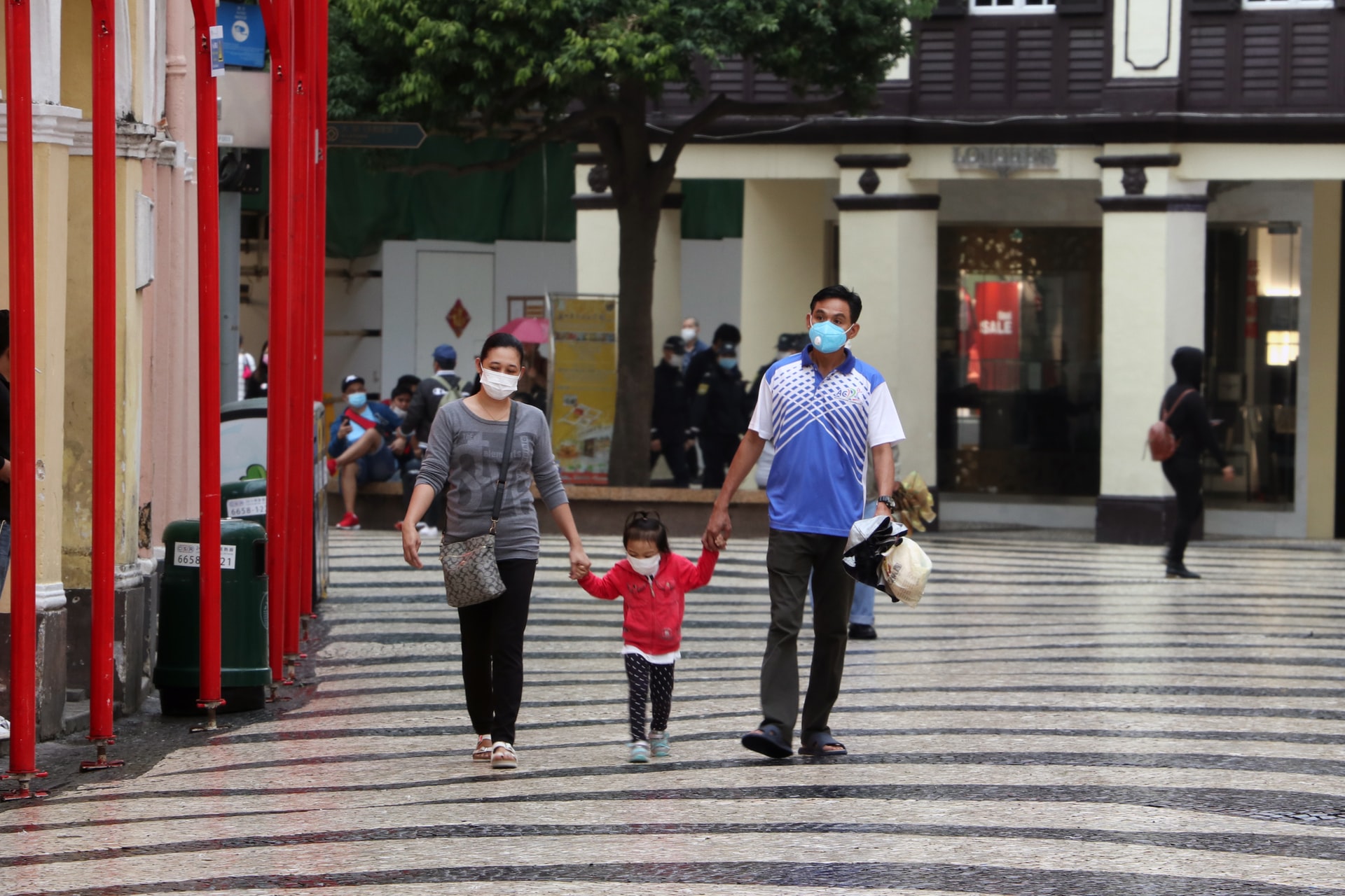 A family wearing masks and walking down the street in Macau