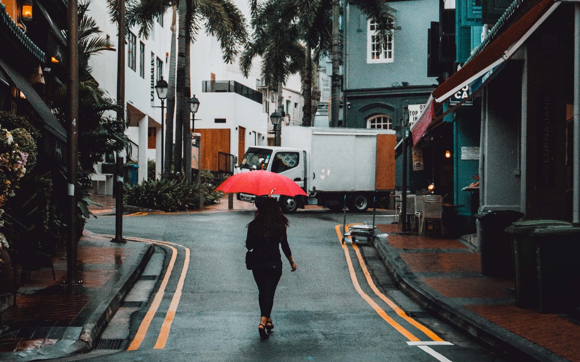 A woman walking down a street with an umbrella in hand
