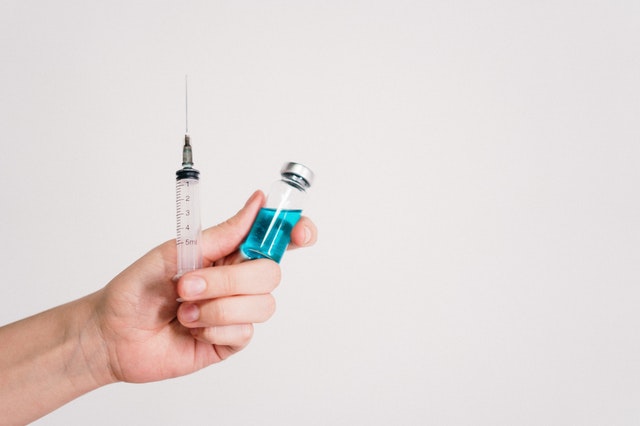 hand holding syringe and vial of blue liquid
